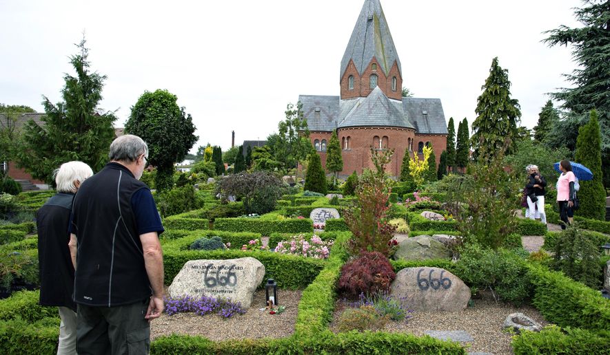 People look at a vandalised tombstone at Hadsund Cemetery, in eastern Jutland, Denmark, Monday July 22, 2019. Some 100 gravestones in Denmark have been found vandalized with graffiti in a cemetery adjacent to Hadsund Church in the eastern part of the Jutland peninsula. Several of the gravestones had "666"written on them with black spray paint and large letters. The church's staff noticed the vandalism early Sunday and immediately alerted the regional police, who are investigating the matter. The perpetrators' motive or motives remains unclear. (Henning Bagger/Ritzau Scanpix via AP)