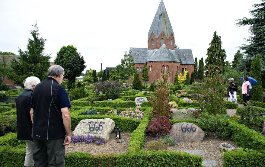 People look at a vandalised tombstone at Hadsund Cemetery, in eastern Jutland, Denmark, Monday July 22, 2019. Some 100 gravestones in Denmark have been found vandalized with graffiti in a cemetery adjacent to Hadsund Church in the eastern part of the Jutland peninsula. Several of the gravestones had "666"written on them with black spray paint and large letters. The church's staff noticed the vandalism early Sunday and immediately alerted the regional police, who are investigating the matter. The perpetrators' motive or motives remains unclear. (Henning Bagger/Ritzau Scanpix via AP)