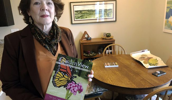 In this July 12, 2019 photo, former Iowa State University administrator Teresa McLaughlin poses at her Coralville, Iowa home with a magazine featuring Nature Connects, the outdoor sculptures made of Lego bricks that she managed. The university has withdrawn allegations of wrongdoing against McLaughlin and paid her $225,000 to settle a legal dispute that derailed the popular art program. (AP Photo/Ryan J. Foley)