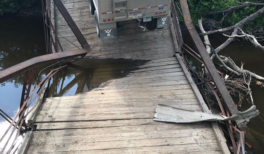 This undated photo provided by Grand Forks County Sheriff's Department shows an overweight semi has caused the collapse of a small, historic bridge near Northwood, N.D. Authorities say the semi, with a trailer load of dry beans, was traveling on the 56-foot-long, restricted-weight bridge over the Goose River Monday, July 22, 2019, when it gave way. (Grand Forks County Sheriff's Department via AP)