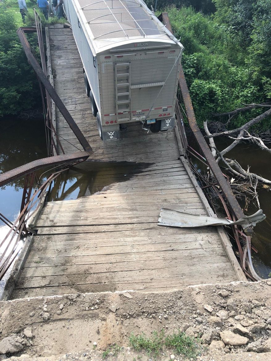 This undated photo provided by Grand Forks County Sheriff's Department shows an overweight semi has caused the collapse of a small, historic bridge near Northwood, N.D. Authorities say the semi, with a trailer load of dry beans, was traveling on the 56-foot-long, restricted-weight bridge over the Goose River Monday, July 22, 2019, when it gave way. (Grand Forks County Sheriff's Department via AP)
