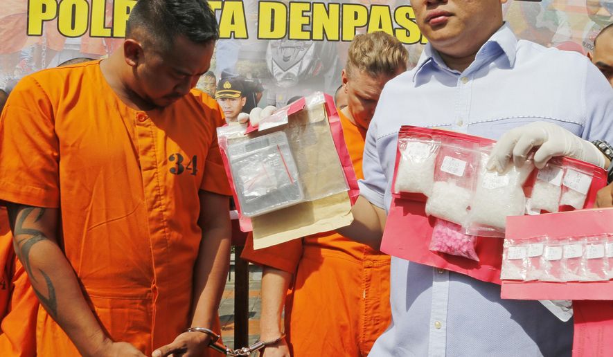 Police officers show evidence as they parade Australian nationals David van Iersel, rear right, and William Cabantog, left, during a press conference at the regional police headquarters in Denpasar, Bali, Indonesia Tuesday, July 23, 2019. Indonesian police say two Australian men have been arrested with cocaine on Bali. (AP Photo/Firdia Lisnawati)