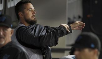 Miami Marlins starting pitcher Caleb Smith puts on his jacket in the dugout after losing a perfect game and no hitter during the sixth inning of a baseball game against the Chicago White Sox Tuesday, July 23, 2019, in Chicago. (AP Photo/Charles Rex Arbogast)