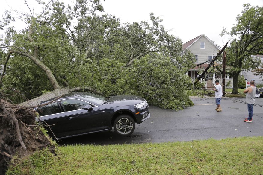 A car is crushed under a large tree in Neptune City, N.J., Tuesday, July 23, 2019. Crews are working to restore electricity for hundreds of thousands of people in New Jersey after powerful storms blew across the state. (AP Photo/Seth Wenig)