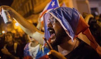 A demonstrator with a Puerto Rican flag in his head protests against Gov. Ricardo Rossello in San Juan, Puerto Rico, Tuesday, July 23, 2019. Protesters are demanding Rossello step down for his involvement in a private chat in which I used profanities to describe an ex- New York City councilwoman and a federal control board overseeing the Island&#39;s finance. (AP Photo /Dennis M. Rivera Pichardo)
