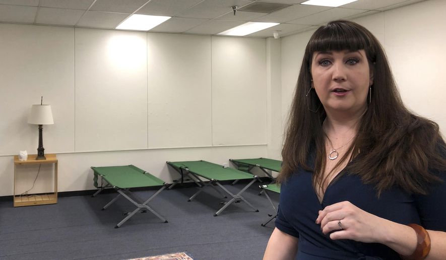 Beth Strano of the International Rescue Committee tours an old elementary school in south Phoenix on Wednesday, July 24, 2019. The school was converted into a shelter to sleep up to 277 people seeking asylum in the U.S. Strano said, the Welcome Center will be able to sleep some 80 adults and children on new cots in the auditorium starting next week and 277 by summer's end. (AP Photo/Anita Snow)