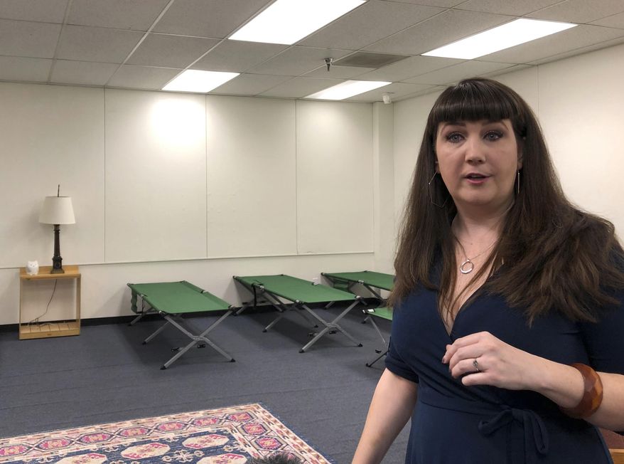 Beth Strano of the International Rescue Committee tours an old elementary school in south Phoenix on Wednesday, July 24, 2019. The school was converted into a shelter to sleep up to 277 people seeking asylum in the U.S. Strano said, the Welcome Center will be able to sleep some 80 adults and children on new cots in the auditorium starting next week and 277 by summer's end. (AP Photo/Anita Snow)