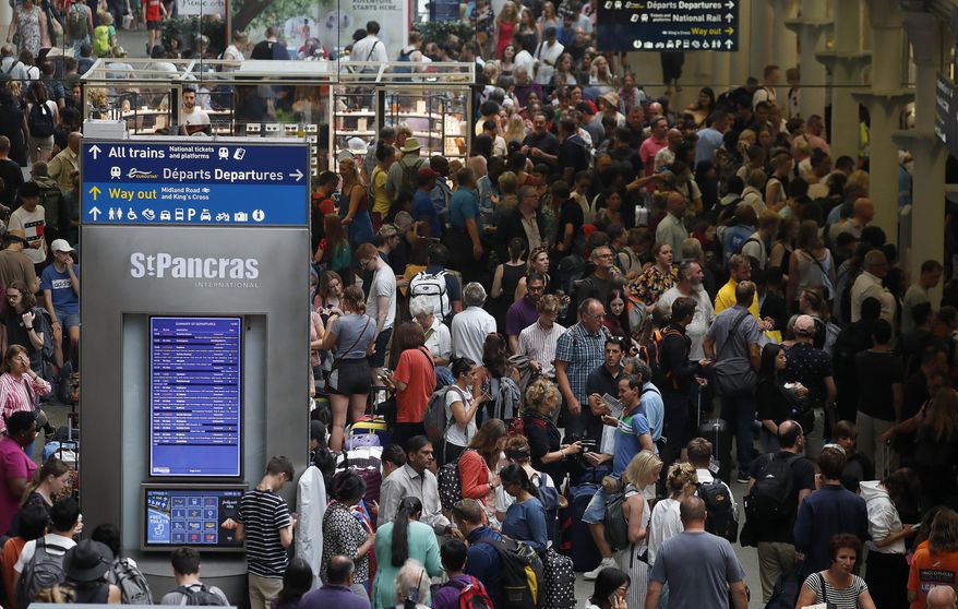 People wait at the St Pancras International train station to board the Eurostar in London, Friday, July 26, 2019. A power outage at one of France's busiest train stations is disrupting travel on the Eurostar to and from London and other routes around the region. (AP Photo/Frank Augstein)
