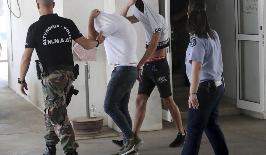 Suspects cover their faces with their shirts as they arrive at the Famagusta courthouse in Paralamni, Cyprus, Friday, July 26, 2019. A Cyprus court has ordered seven Israelis who were vacationing on the east Mediterranean island nation to be detained after a 19-year-old British woman alleged that she was raped in the resort town of Ayia Napa. (AP Photo/Petros Karadjias)