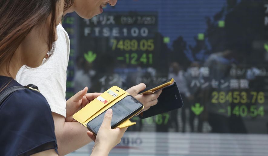 People walk by an electronic stock board of a securities firm in Tokyo, Friday, July 26, 2019. Asian shares are lower Friday as investors continued to watch the brewing trade conflict between China and the U.S., and any signs of what's in store from central banks. (AP Photo/Koji Sasahara)