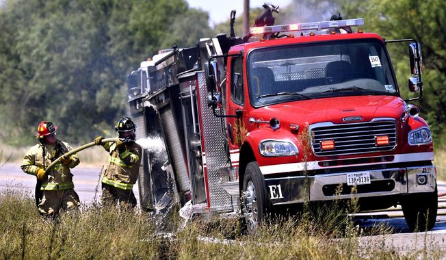 In this Thursday, July 25, 2019 photo, Abilene firefighters hose-down a Snyder Fire Department truck that caught fire on Westlake Road as it was being driven to a maintenance shop in Abilene, Texas. (Ronald W. Erdrich/The Abilene Reporter-News via AP)