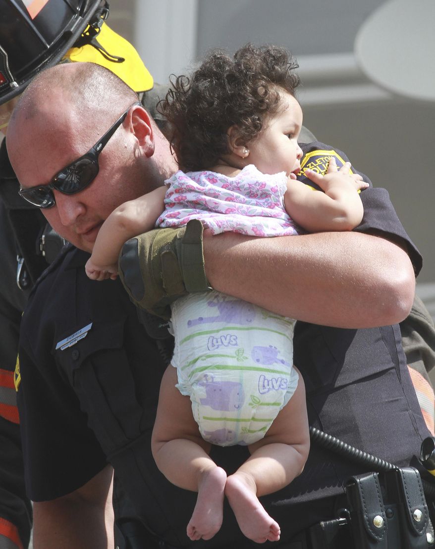 A firefighter holds a child after a fire broke out in Hazleton, Pa., Friday July 26, 2019. City firefighters used aerial truck to rescue occupants from the third floor of the building. Prestigio Restaurant and apartments were damaged by the fire. (Warren Ruda/Hazleton Standard-Speaker via AP)