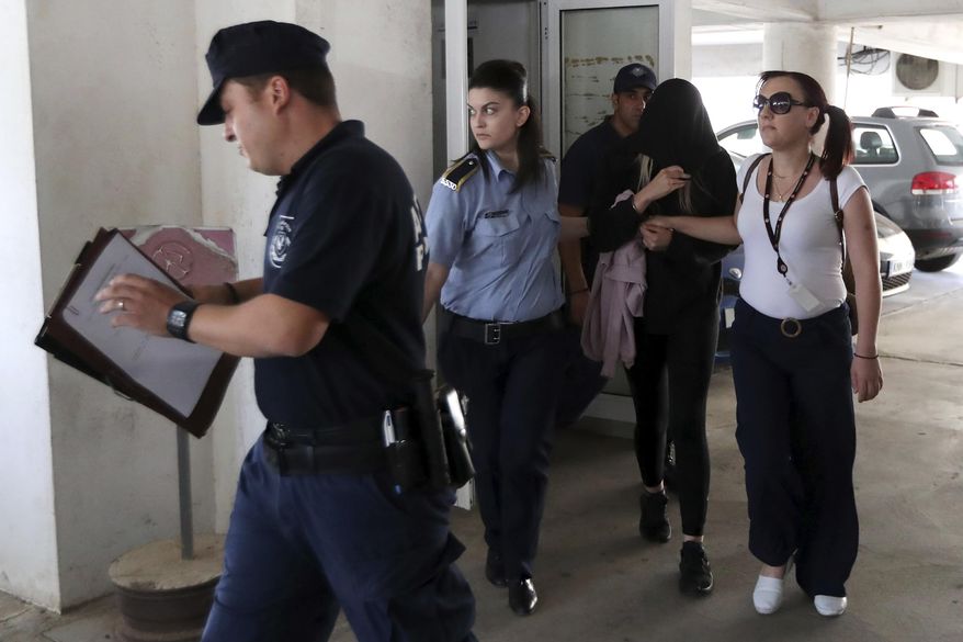 Police officers escort a 19-year-old British woman, second from right, out of Famagusta court in town of Paralimni, Cyprus, Monday, July 29, 2019. The 19-year-old British woman has been arrested on suspicion of filing a false complaint of gang rape for which a dozen Israeli teens were held, Cyprus police say. (AP Photo/Petros Karadjias)