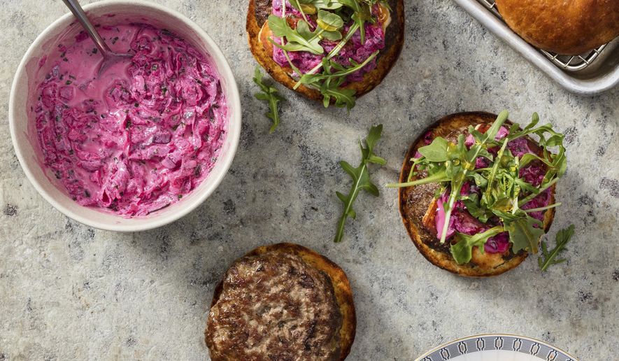 This undated photo provided by America's Test Kitchen in July 2019 shows Lamb Burgers with Halloumi and Beet Tzatziki in Brookline, Mass. This recipe appears in the cookbook “The Ultimate Burger.” (Daniel J. van Ackere/America's Test Kitchen via AP)