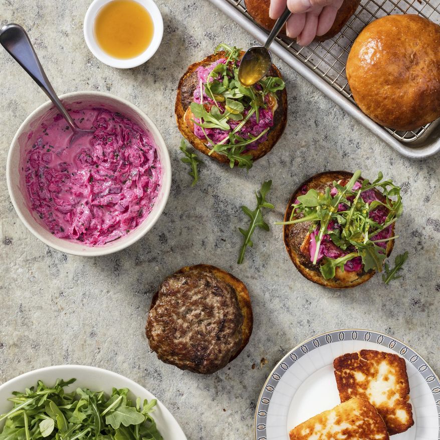 This undated photo provided by America's Test Kitchen in July 2019 shows Lamb Burgers with Halloumi and Beet Tzatziki in Brookline, Mass. This recipe appears in the cookbook “The Ultimate Burger.” (Daniel J. van Ackere/America's Test Kitchen via AP)