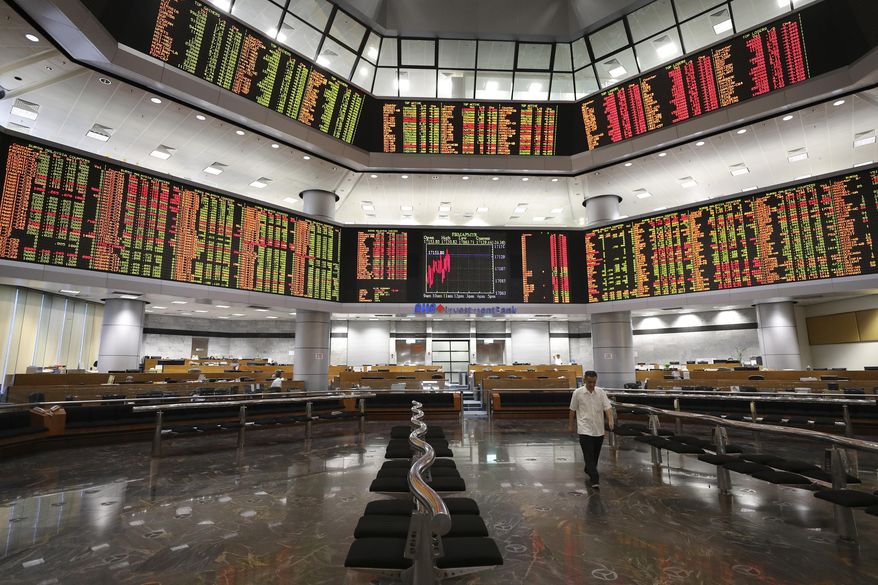 An investor walks in front of stock trading boards at a private stock market gallery in Kuala Lumpur, Malaysia, Monday, July 29, 2019. Asian shares were mostly lower Monday as investors watched for developments in the trade conflict between the U.S. and China, with talks set to continue this week. (AP Photo/Vincent Thian)