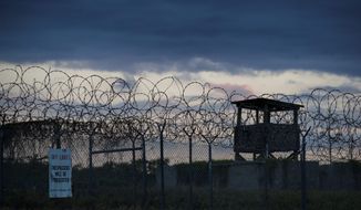 In this photo reviewed by U.S. military officials, the sun sets behind the closed Camp X-Ray detention facility, Wednesday, April 17, 2019, in Guantanamo Bay Naval Base, Cuba. (AP Photo/Alex Brandon)