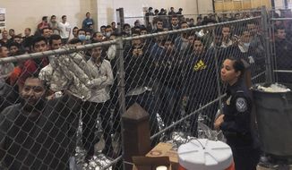 In this July 12, 2019 file photo, men stand in a U.S. Immigration and Border Enforcement detention center in McAllen, Texas, during a visit by Vice President Mike Pence.  Immigration lawyers say a pattern has repeated itself for several weeks in migrant detention facilities along the border. Immigrants are being detained in packed cells only to be transferred out within hours once the government is sued on their behalf. (Josh Dawsey/The Washington Post via AP, Pool)