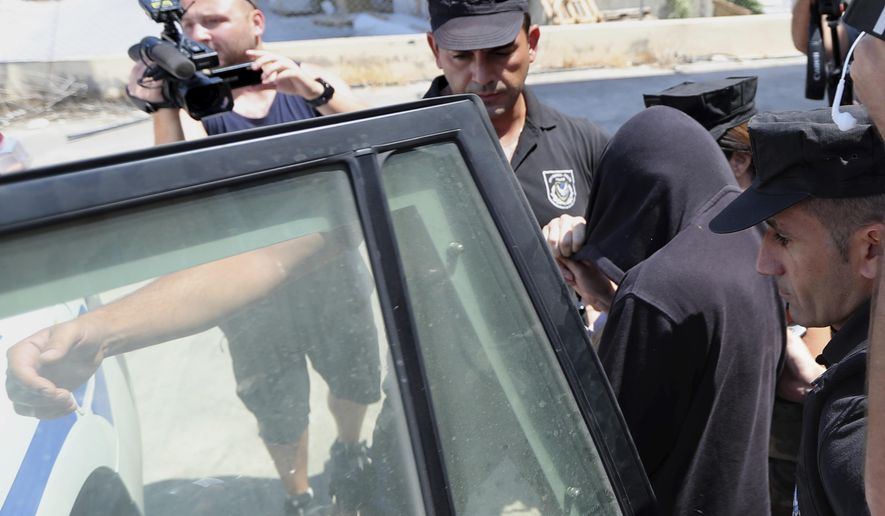 Elite police unit officers escort a 19-year old British woman, with head covered, from the Famagusta court in Paralimni, Cyprus, Tuesday, July 30, 2019, after her case was postponed. The British woman faces a public nuisance charge after she admitted that her accusation that 12 Israeli teens raped her at a popular resort town was untrue. (AP Photo/Petros Karadjias)