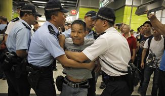 Police restrain an angry passenger who tried to fight with protesters in Hong Kong on Tuesday, July 30, 2019. Protesters in Hong Kong have disrupted subway service during the morning commute by blocking the doors on trains, preventing them from leaving the stations. (AP Photo/Vincent Yu)