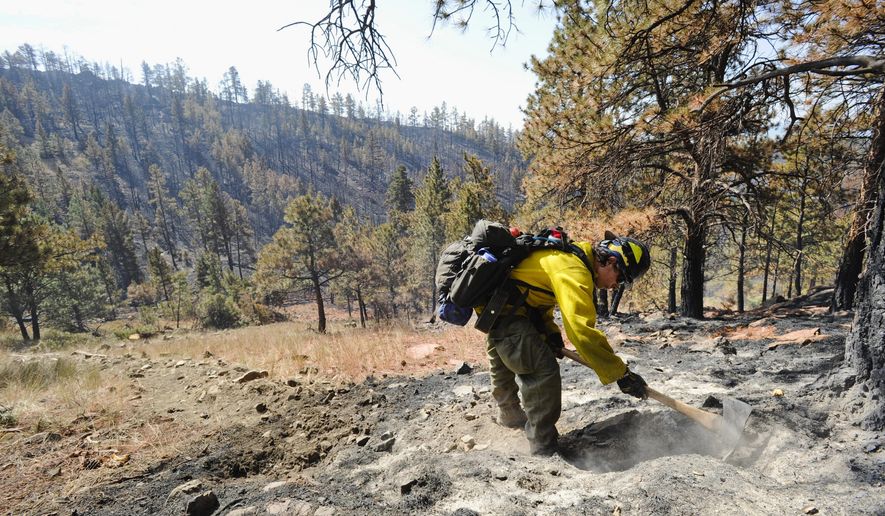 Ben Dallas works a hot spot near a residence of the North Hills Fire Tuesday, July 30, 2019 in Helena, Mont. Montana residents who fled their homes because of a four-day wildfire were allowed back to gather important belongings as Oregon authorities warned of unhealthy air because of another blaze that sent smoke wafting over a key highway and drifting more than 50 miles (80 kilometers) to the state's border with California. (Thom Bridge/Independent Record via AP)