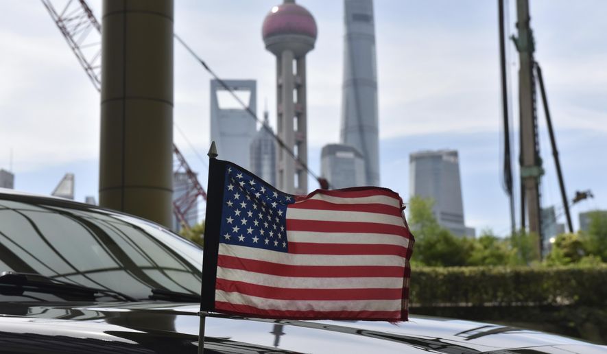 A U.S. flag flies on a U.S. consulate car, with the backdrop of buildings in the Lujiazui financial district, outside a hotel where U.S. trade negotiators are staying, in Shanghai Wednesday, July 31, 2019. (Greg Baker/Pool Photo via AP)