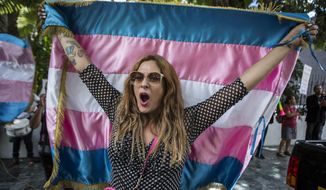A protester who identifies as transgender waves a transgender flag during a protest against a deal Guatemalan President Jimmy Morales&#x27; government signed with Washington that would force Salvadoran and Honduran migrants to request asylum in Guatemala instead of the United States, in Guatemala City, Wednesday, July 31, 2019. Critics of the deal point out that Guatemala has the same problems that are driving Hondurans and Salvadorans to flee their homes: violence, poverty, joblessness and a prolonged drought that has severely hurt farmers. (AP Photo/ Oliver de Ros) **FILE**
