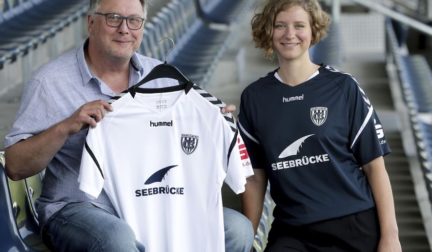 Thoralf Hintze, left, member of the board of the German fourth division soccer club Babelsberg 03, and Liza Pflaum, spokeswomen of the 'Seebruecke' (Pier) sea rescue organistion pose for the photographers after a press conference in Potsdam near Berlin, Germany, Thursday, Aug. 1, 2019. Babelsberg 03 provides its current season team jersey to the international 'Seebruecke' movement. (AP Photo/Michael Sohn)