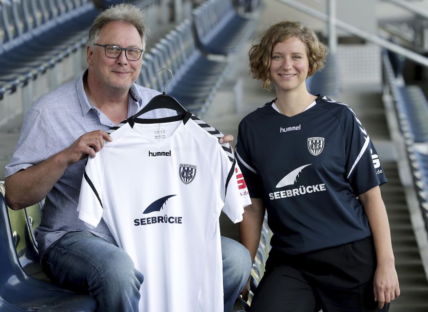 Thoralf Hintze, left, member of the board of the German fourth division soccer club Babelsberg 03, and Liza Pflaum, spokeswomen of the 'Seebruecke' (Pier) sea rescue organistion pose for the photographers after a press conference in Potsdam near Berlin, Germany, Thursday, Aug. 1, 2019. Babelsberg 03 provides its current season team jersey to the international 'Seebruecke' movement. (AP Photo/Michael Sohn)