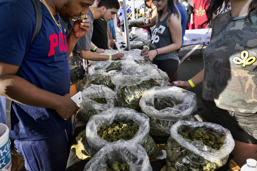 FILE - In this Oct. 20, 2018, file photo, a customer takes a sniff test from the selection of marijuana strains at Miyagi LA booth at the cannabis-themed Kushstock Festival at Adelanto, Calif. California Bureau of Cannabis Control have reopened funding applications for marijuana social equity programs after unspecified delays. Regulators say California cities and counties must apply by Aug. 30, 2019, to receive a portion of the $10 million in Legislature-established funds. (AP Photo/Richard Vogel, File)