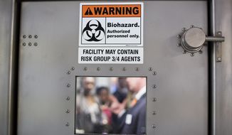 FILE-In this Tuesday, Aug. 11, 2015 file photo, a warning sign is posted to the door of a medevac biocontainment unit aboard a military transport plane at Dobbins Air Force Reserve Base during a media tour, in Marietta, Ga. Some of the first Ebola virus patients to be successfully treated in the United States are reuniting five years later with the medical team that treated them at Emory University Hospital in Atlanta. (AP Photo/David Goldman, File)