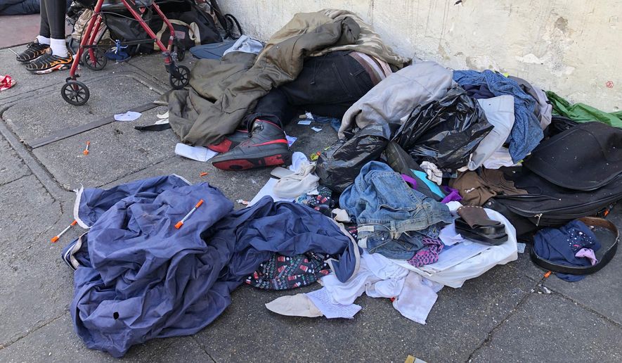 In this photo taken July 25, 2019, sleeping people, discarded clothes and used needles sit across the street from a staffed &amp;quot;Pit Stop&amp;quot; public toilet in the Tenderloin neighborhood in San Francisco. Merchants say the bathrooms have given homeless and other people a private place to go so they don&#39;t sully sidewalks as much. (AP Photo/Janie Har)