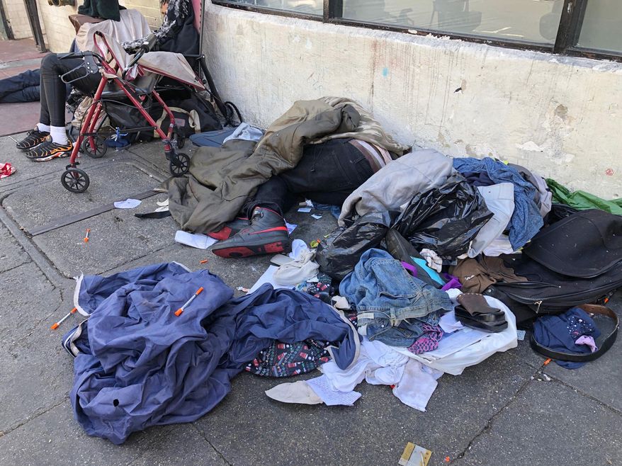 In this photo taken July 25, 2019, sleeping people, discarded clothes and used needles sit across the street from a staffed &amp;quot;Pit Stop&amp;quot; public toilet in the Tenderloin neighborhood in San Francisco. Merchants say the bathrooms have given homeless and other people a private place to go so they don&#39;t sully sidewalks as much. (AP Photo/Janie Har)