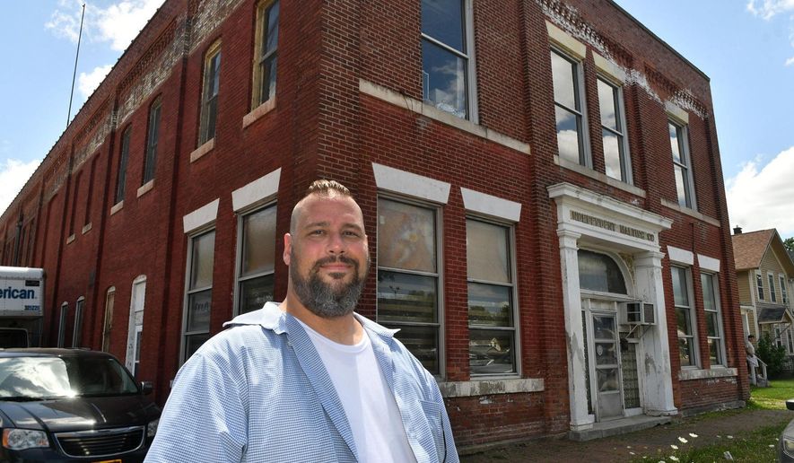 In this Monday, July 15, 2019 photo, Andrew Arnold stands in front of the Independent Malting Company in Davenport, Iowa. Arnold loves local history and good beer. The 42-year-old Davenport native is mixing those passions in an intoxicating plan to create a new $2.5 million craft brewery, museum and tasting room at the site of what was once Iowa's largest brewery, Independent Malting Company. (Gary Kranbeck/Quad City Times via AP)