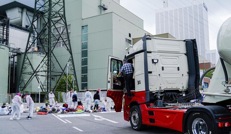 Dozens of environmentalists block the main entrance of the coal-fired power plant in Mannheim, Germany, Aug. 3, 2019. People are blocking the entrance to a coal-fired power plant in the German city in protest over the burning of fossil fuels. Mannheim police said about 40-50 protesters have been staging the blockade since in the early hours of Saturday. (Uwe Anspach/dpa via AP)
