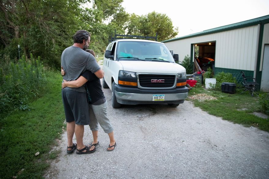 Matt Hall, left, hugs his wife Terra before she leaves for a farmers market Saturday, July 20, 2019, in Missouri Valley, Iowa. The Hall's Rhizosphere Farm will close at the end of the growing season. (Ryan Soderlin/The World-Herald via AP)