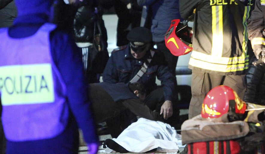 FILE - In this Dec. 8, 2018 file photo a man touches a lifeless body on the ground outside disco Lanterna Azzurra in Corinaldo, central Italy, Saturday, after a stampede at a rap concert killed five young teenagers and a woman who had accompanied her daughter to the event. Italian police have arrested six men on charges of manslaughter for allegedly using pepper spray to carry out thefts at a concert for teens, triggering a stampede that killed six people. (AP Photo/Bobo Antic)