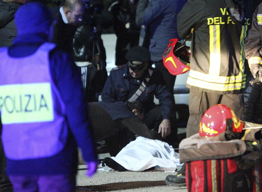 FILE - In this Dec. 8, 2018 file photo a man touches a lifeless body on the ground outside disco Lanterna Azzurra in Corinaldo, central Italy, Saturday, after a stampede at a rap concert killed five young teenagers and a woman who had accompanied her daughter to the event. Italian police have arrested six men on charges of manslaughter for allegedly using pepper spray to carry out thefts at a concert for teens, triggering a stampede that killed six people. (AP Photo/Bobo Antic)