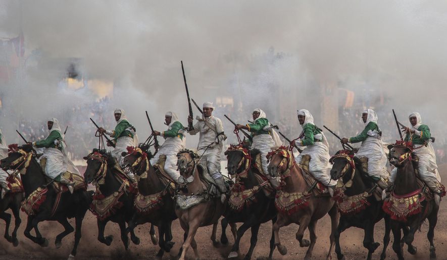 In this Thursday, July 25, 2019 photo, a troupe charges firing their rifles during Tabourida, a traditional horse riding show also known as Fantasia, in the coastal town of El Jadida, Morocco. Thousands of visitors descend on the Moroccan coastal city of El Jadida each July to attend the largest equestrian show in the kingdom _ a breathtaking horseback performance that combines synchronized riding with decorative guns. (AP Photo/Mosa'ab Elshamy)