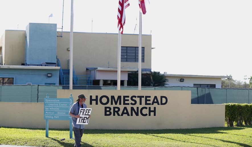 FILE - In this Feb. 19, 2019 file photo, Josh Rubin demonstrates in front of the Homestead Temporary Shelter for Unaccompanied Children, in Homestead, Fla. Federal officials say the Florida detention camp that has housed thousands of migrant children is emptying out. Health and Human Services Department spokeswoman Evelyn Stauffer said in an email Saturday, Aug. 3, that all children are either with family members or at smaller state-licensed facilities. The camp has housed about 14,300 undocumented children since March 2018.(AP Photo/Wilfredo Lee, File)