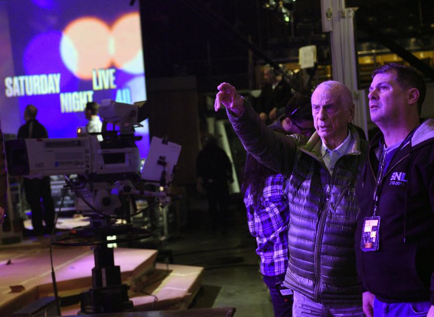 This Feb. 3, 2015 photo released by NBC shows lighting designer Phil Hymes, second right, with lighting director Geoff Amoral on the set of "Saturday Night Live," in New York. NBC says Emmy-winning lighting director Hymes has died. He was 96, and worked on “Saturday Night Live” until 2018. NBC said that Hymes died of complications from cancer at a New York City hospital Monday, Aug. 29, 2019. (Dana Edelson/NBC via AP)