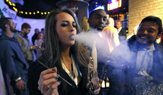 In this Dec. 31, 2013, photo, a woman smokes marijuana during a Prohibition-era-themed New Year&#39;s Eve party at a bar in Denver, the day before Colorado allowed retail sales of marijuana to those 21 and over.  (AP Photo/Brennan Linsley) **FILE**