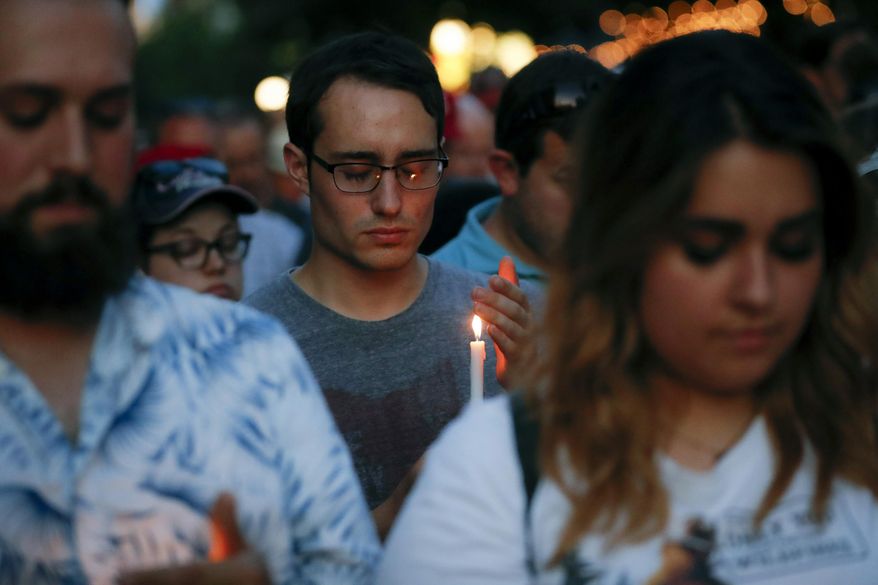 Mourners bow their heads in prayer as they gather for a vigil at the scene of a mass shooting, Sunday, Aug. 4, 2019, in Dayton, Ohio. Multiple people in Ohio were killed in the second mass shooting in the U.S. in less than 24 hours. (AP Photo/John Minchillo)