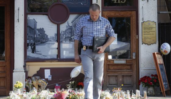 A Dayton Police officer performs a grid search beside a makeshift memorial for the slain and injured in the Oregon District after a mass shooting that occurred early Sunday morning, Tuesday, Aug. 6, 2019, in Dayton.  Facing pressure to take action after the latest mass shooting in the U.S., Ohio&#x27;s Republican governor urged the GOP-led state Legislature Tuesday to pass laws requiring background checks for nearly all gun sales and allowing courts to restrict firearms access for people perceived as threats.  (AP Photo/John Minchillo)