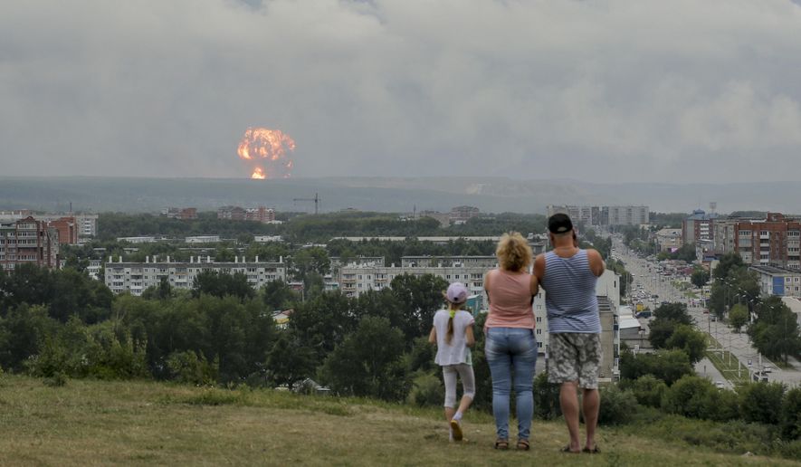 In this photo taken on Monday, Aug. 5, 2019, a family watches explosions at a military ammunition depot near the city of Achinsk in eastern Siberia's Krasnoyarsk region, in Achinsk, Russia. Russian officials say powerful explosions at a military depot in Siberia left 12 people injured and one missing and forced over 16,500 people to leave their homes. (AP Photo/Dmitry Dub)