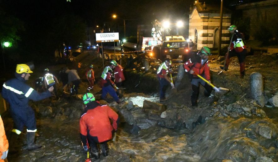 Rescuers work to clear mud from a road in Codesino, near the northern Italian town of Lecco, in the early hours of Wednesday, Aug. 7, 2019. Italian firefighters say 200 people have been evacuated following a Tuesday landslide in a mountainous area in the northern Lombardy region. (Daniele Bennati/ANSA via AP)
