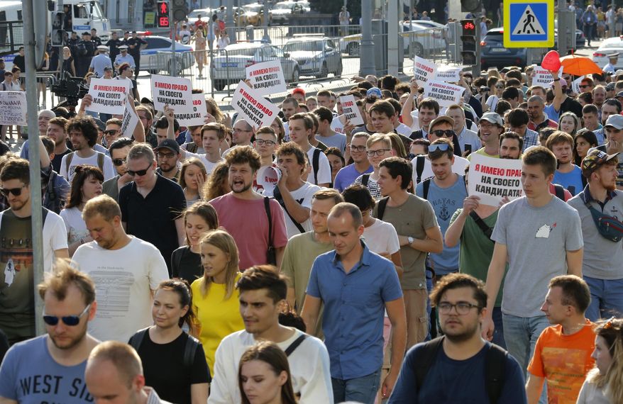 FiLE - In this file photo dated Saturday, July 27, 2019, protesters hold posters that read: "I have the right to my candidate" during an unsanctioned rally in the center of Moscow, Russia. Moscow’s children’s rights ombudsman and other public figures Wednesday Aug. 7, 2019, have reacted with outrage to Russian prosecutors’ moves to strip a couple of custody of their 1-year old son for allegedly taking him to this unauthorized protest on July 27. (AP Photo/Alexander Zemlianichenko, FILE)