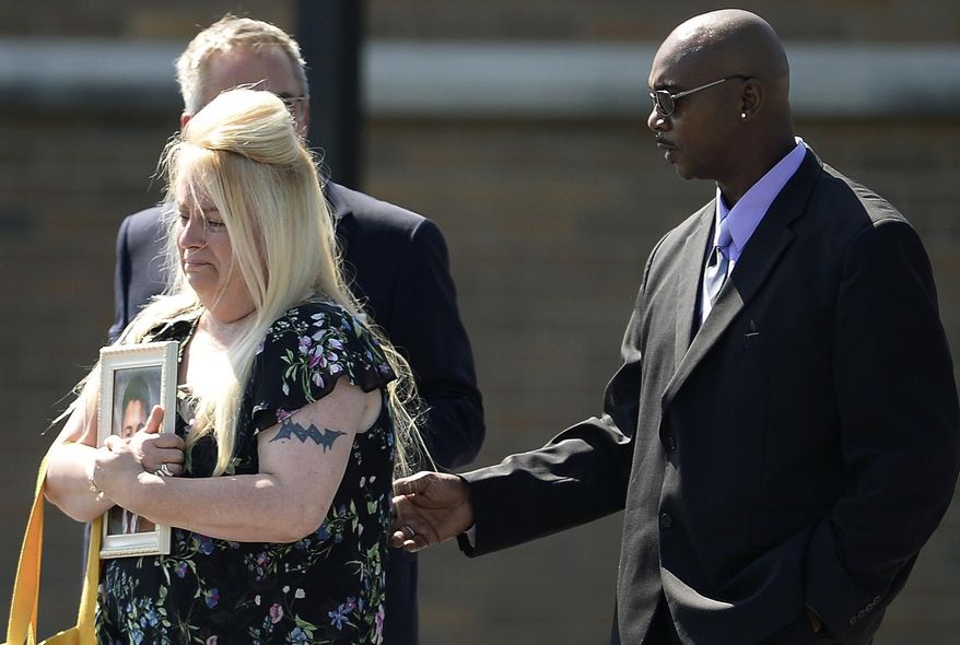 Tammy Williams, left, holds a photo of her son Trevor Irby, 25, as she and her husband Will leave a funeral service in Romulus, N.Y., Thursday, Aug. 8, 2019. Irby and two others were killed July 28 when Santino William Legan cut through a fence and opened fire with a Romanian-made AK-47 style-rifle at the popular Gilroy Garlic Festival. (AP Photo/Adrian Kraus)