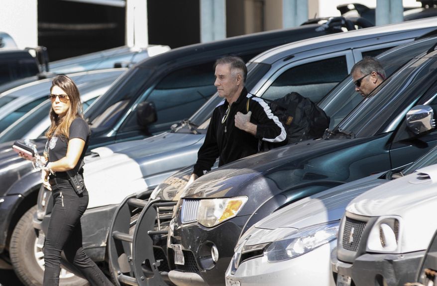 Brazilian businessman Eike Batista, center, is escorted to a police station in Rio de Janeiro, Brazil, Thursday, Aug. 8, 2019. Brazil's federal police say that Batista was arrested on suspicion of market manipulation and money laundering. (AP Photo/Bruno Rocha)