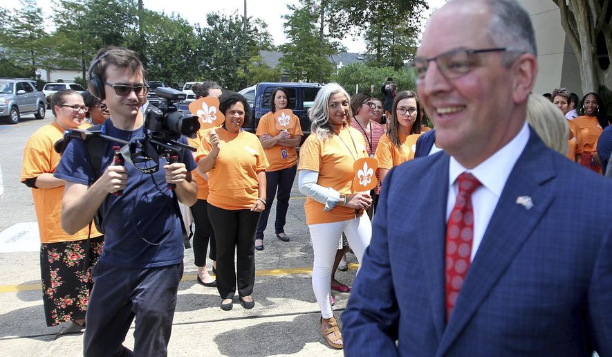 Orange-shirted employees of a Medicaid managed company which did not receive a contract renewal from the Edwards administration silently protest as Louisiana Governor John Bel Edwards leaves the Louisiana Secretary of State&#39;s office after he signed up to run in the upcoming election, in Baton Rouge, La., Tuesday, August 6, 2019. The candidate sign-up period for Louisiana&#39;s statewide elections ends Thursday, with the governor&#39;s race at the top of the ballot. (AP Photo/Michael DeMocker)